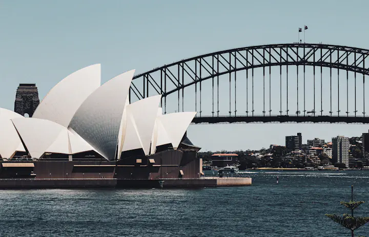 Sydney Opera House beside the harbour with the Sydney Harbour Bridge behind it.