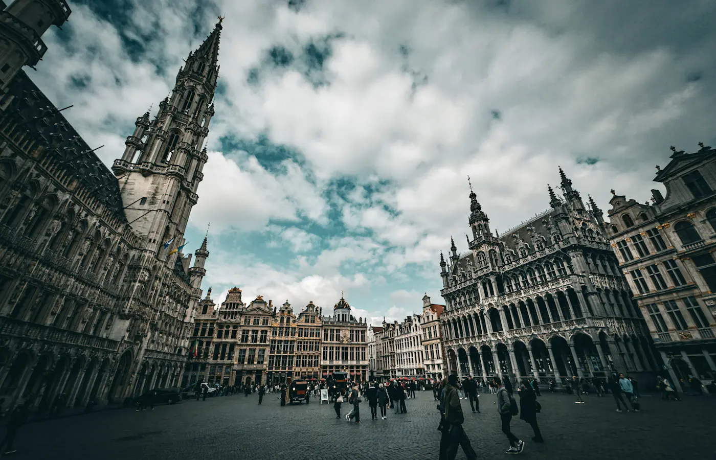 Gabled historic buildings around Grand Place in Brussels beneath a cloudy sky.
