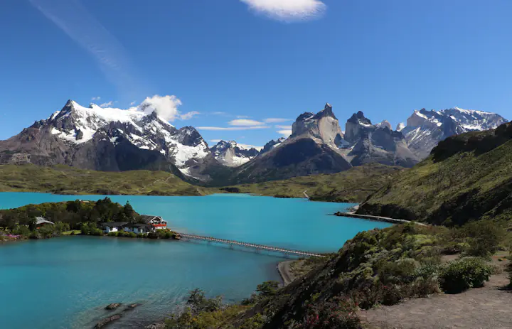 Een turquoise meer, een voetbrug en scherpe bergtoppen in Nationaal Park Torres del Paine, Chili.