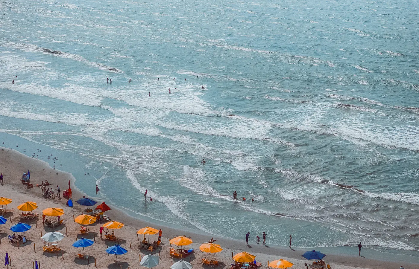 Parasole plażowe i pływacy wzdłuż wybrzeża Cartageny w Kolumbii