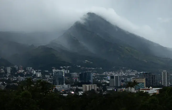 Gratte-ciel de San Salvador sous une crête enveloppée de nuages.