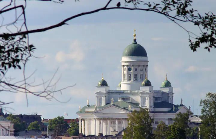 Der Dom von Helsinki mit seiner grünen zentralen Kuppel, eingerahmt von Baumzweigen in Finnland