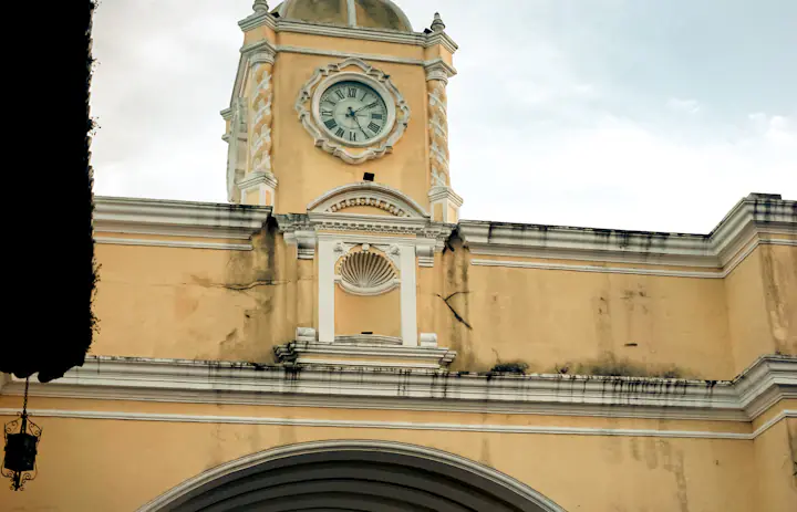 Zbliżenie żółtego łuku Santa Catalina i wieży zegarowej w Antigua Guatemala