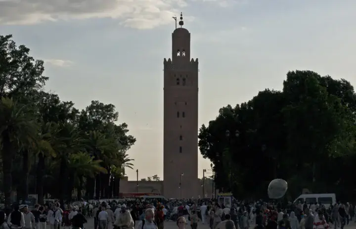 Koutoubia-Minarett hinter Menschen, die in der Nähe des Jemaa el-Fnaa in Marrakesch gehen