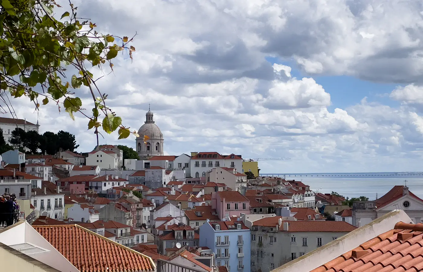 Tetti rossi del quartiere Alfama di Lisbona, con il Pantheon Nazionale e il Tago sullo sfondo.