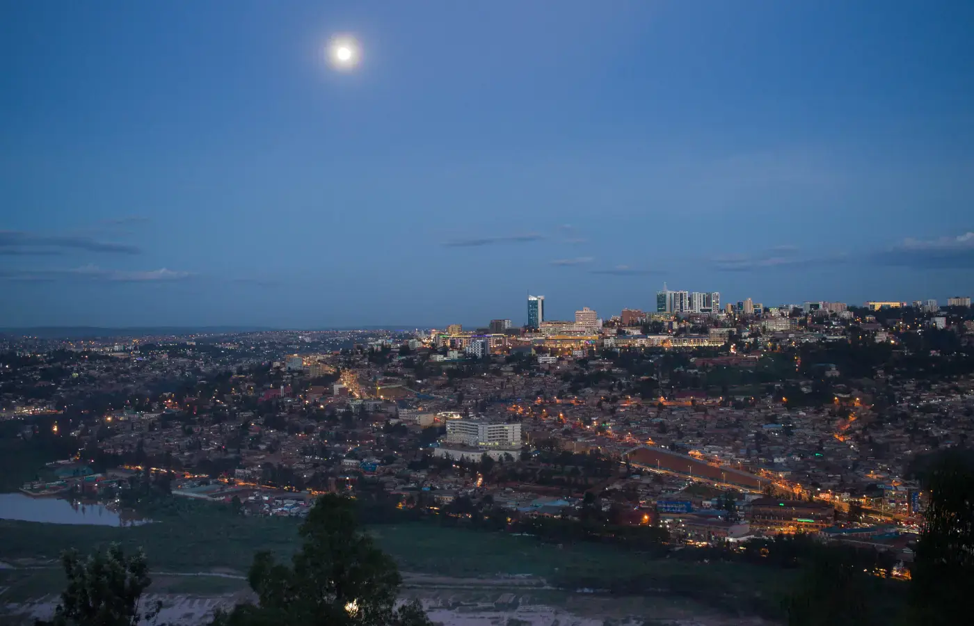 Skyline serale del centro di Kigali con luci sulle colline sotto la luna, Ruanda.