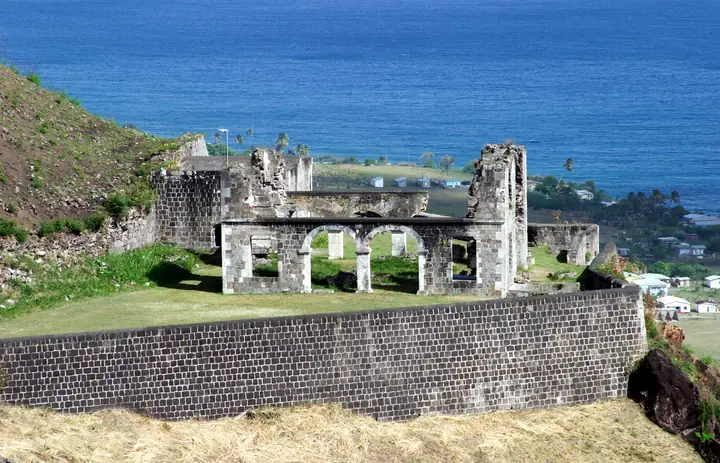Ruined stone fortifications at Brimstone Hill Fortress rising above the Saint Kitts coastline.