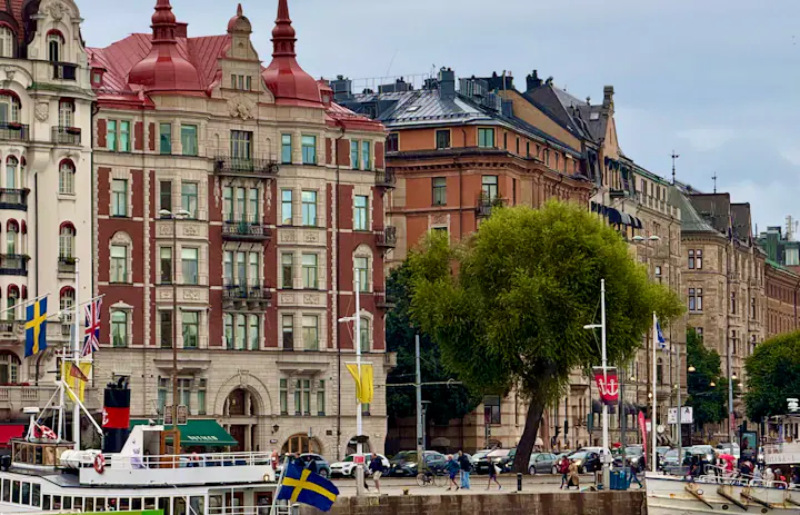 Frente marítima de Estocolmo com edifícios históricos e barcos com bandeira sueca