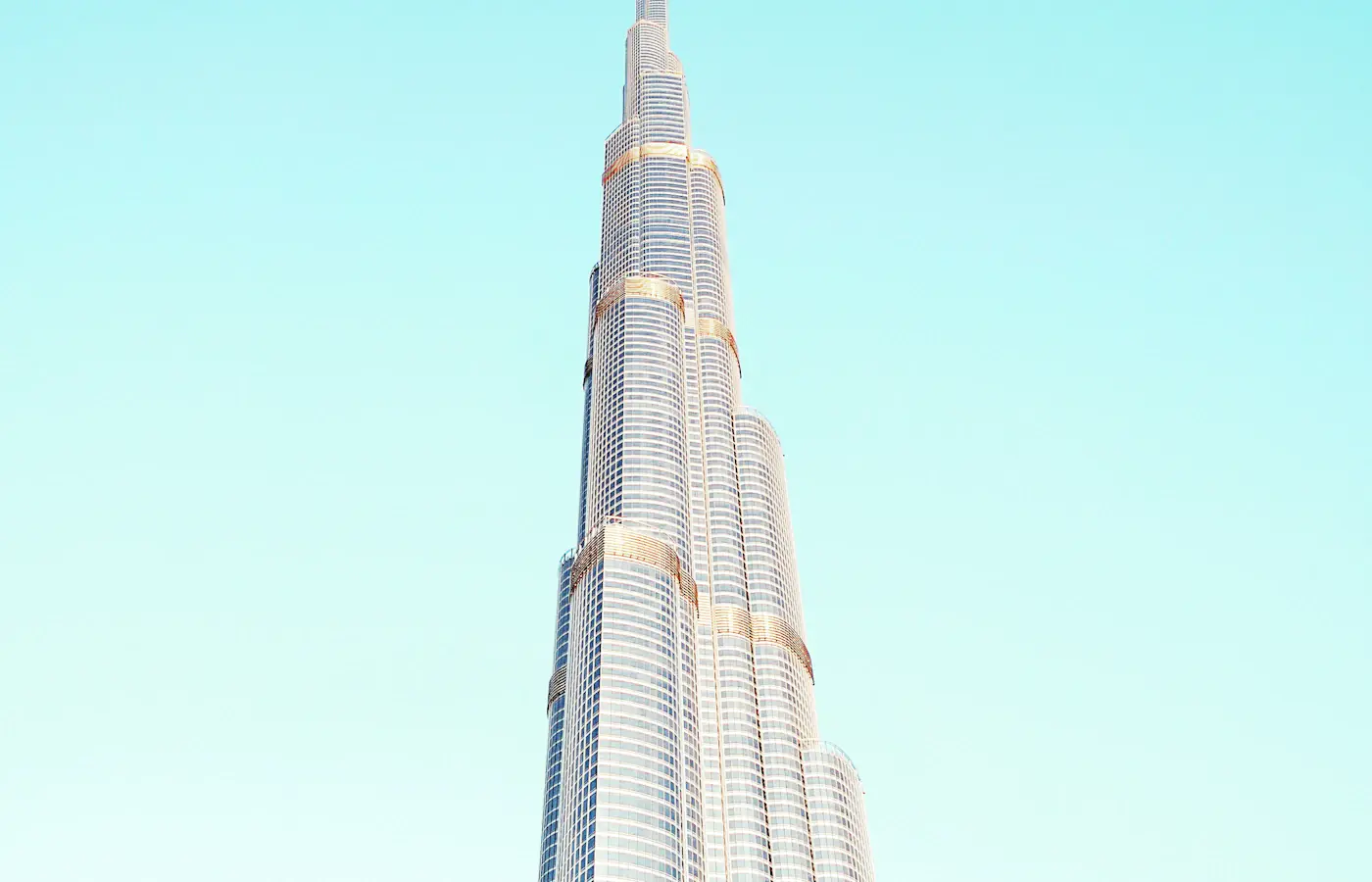 Burj Khalifa's stepped glass tower against a pale blue Dubai sky